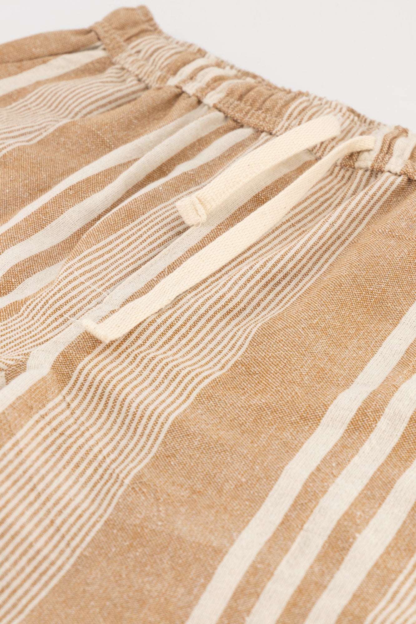 Flat-lay detail shot of brown striped cotton kikoi shorts.