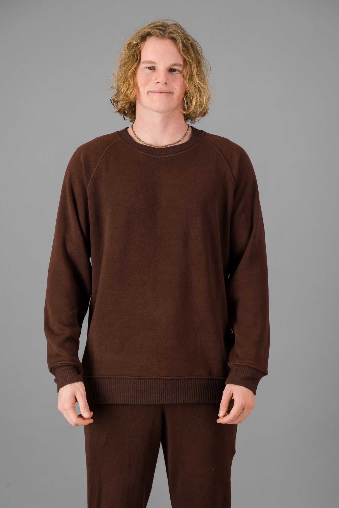 A man in a Chocolate Cashmere-Feel Crew Neck Sweater and matching joggers.