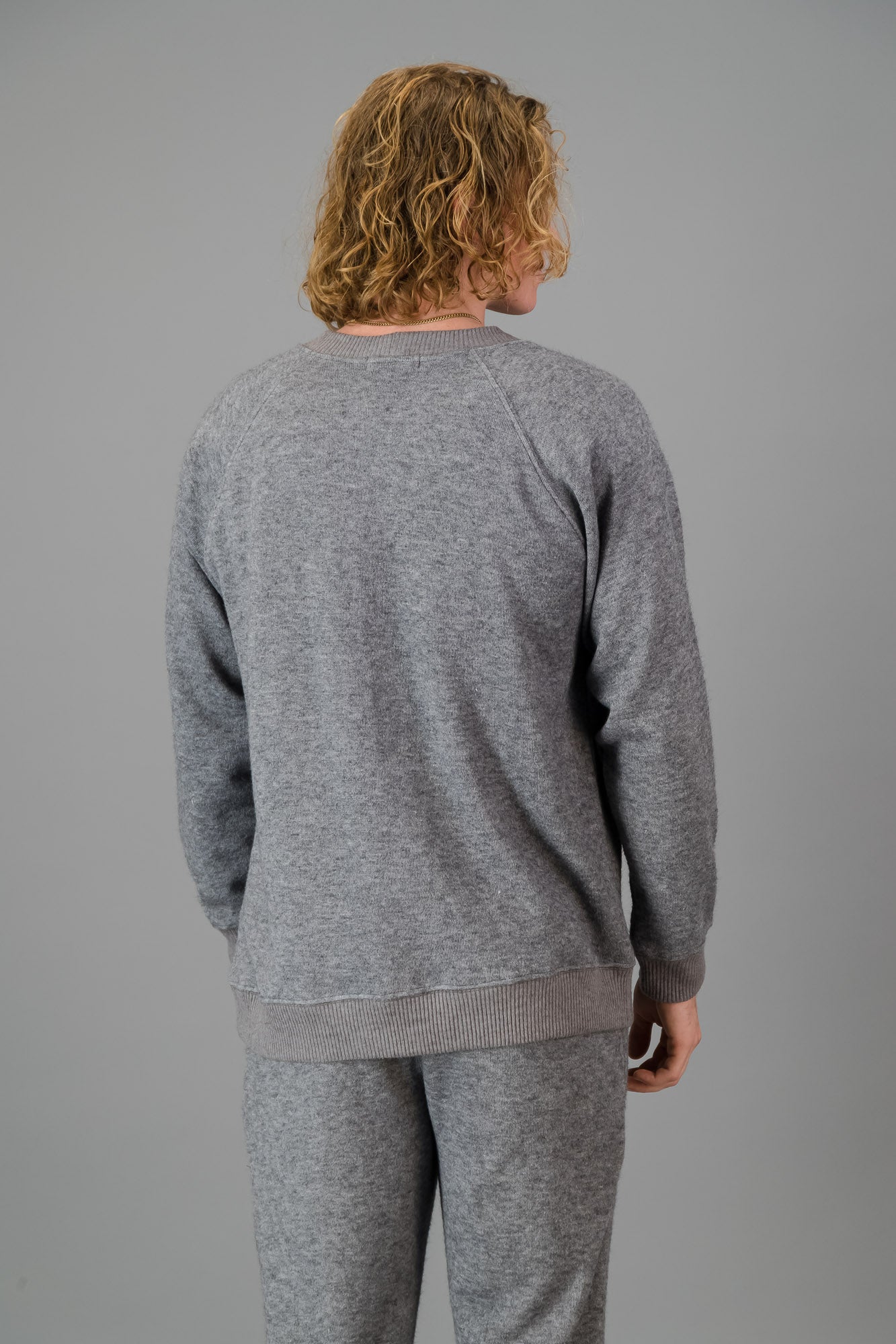 A man in a Grey Cashmere-Feel Crew Neck Sweater and matching joggers.