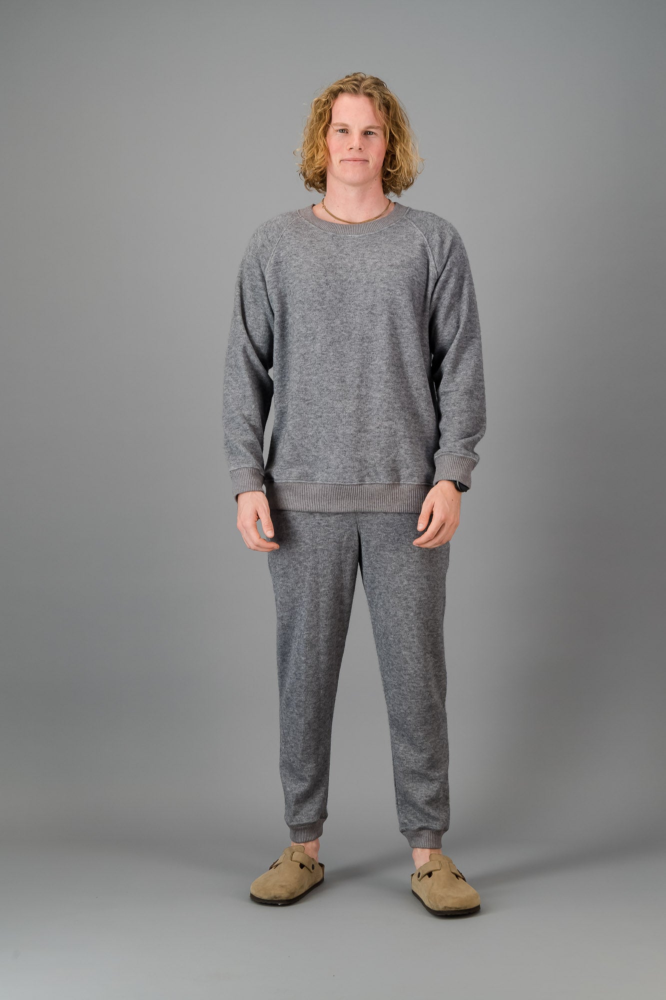 A man in a Grey Cashmere-Feel Crew Neck Sweater and matching joggers.