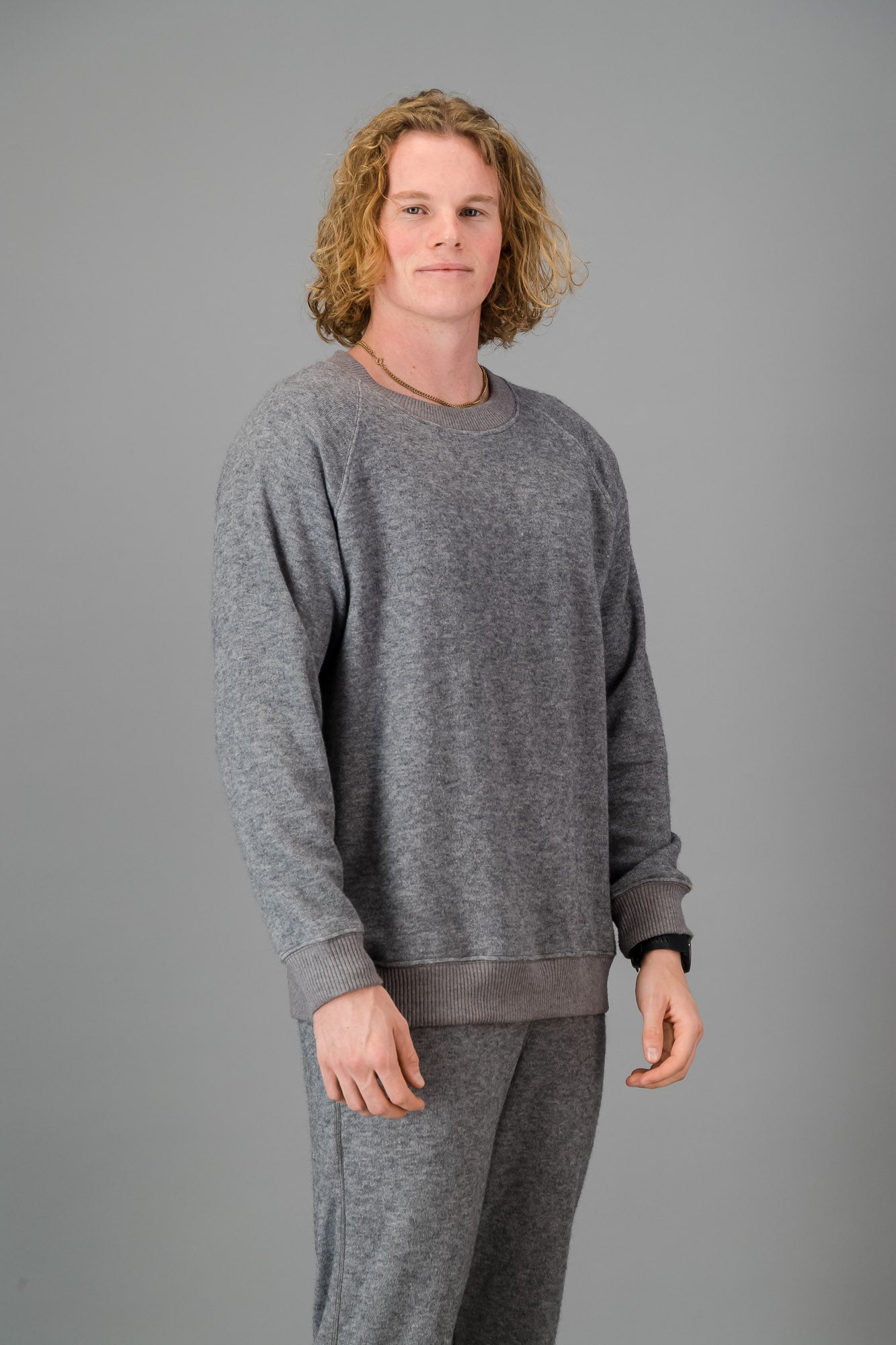 A man in a Grey Cashmere-Feel Crew Neck Sweater and matching joggers.