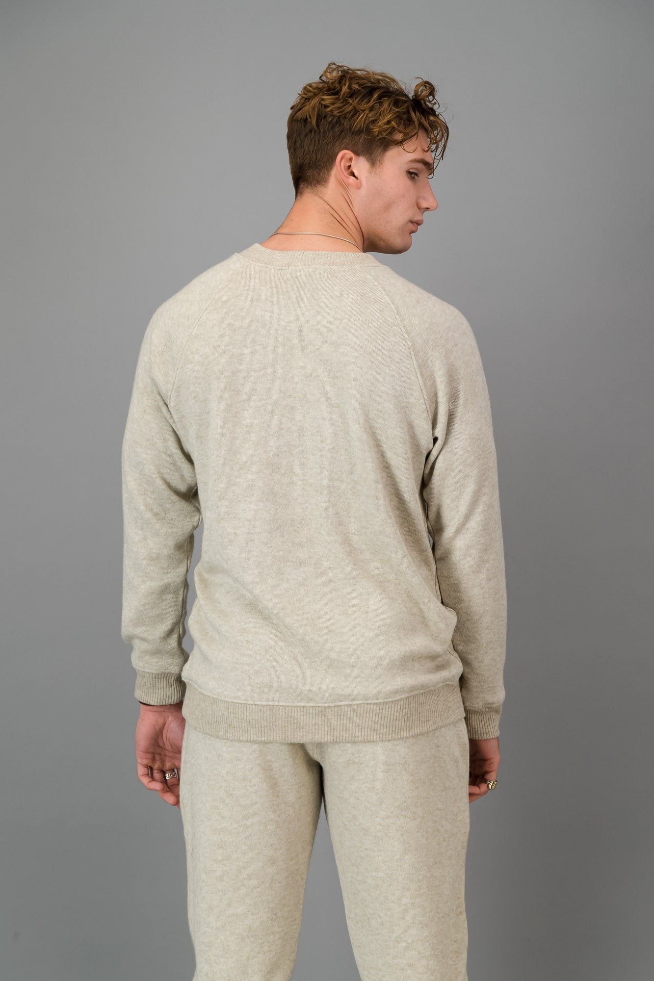 A man in Oatmeal Cashmere-Feel Crew Neck Sweater and matching joggers.