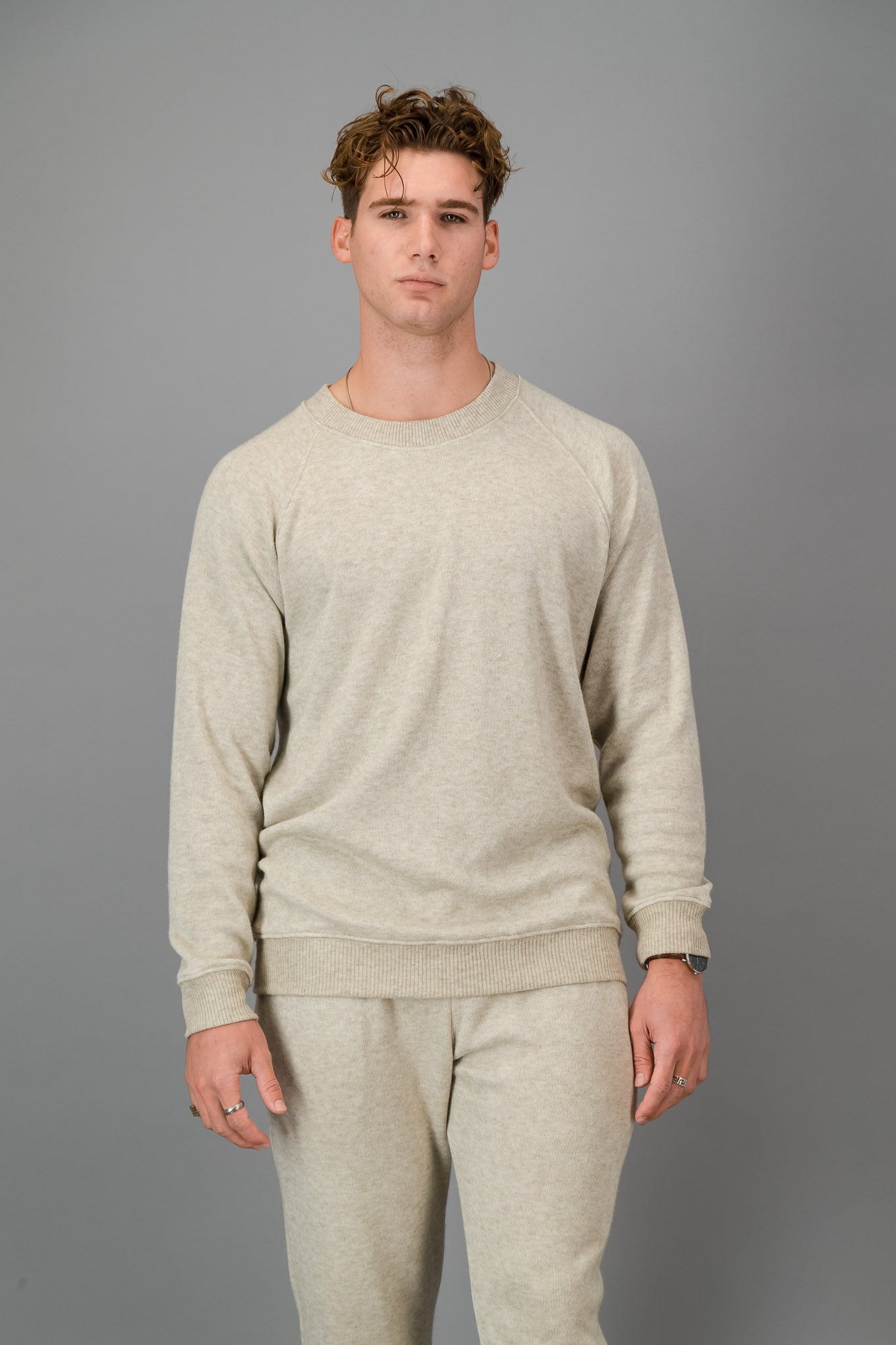 A man in Oatmeal Cashmere-Feel Crew Neck Sweater and matching joggers.