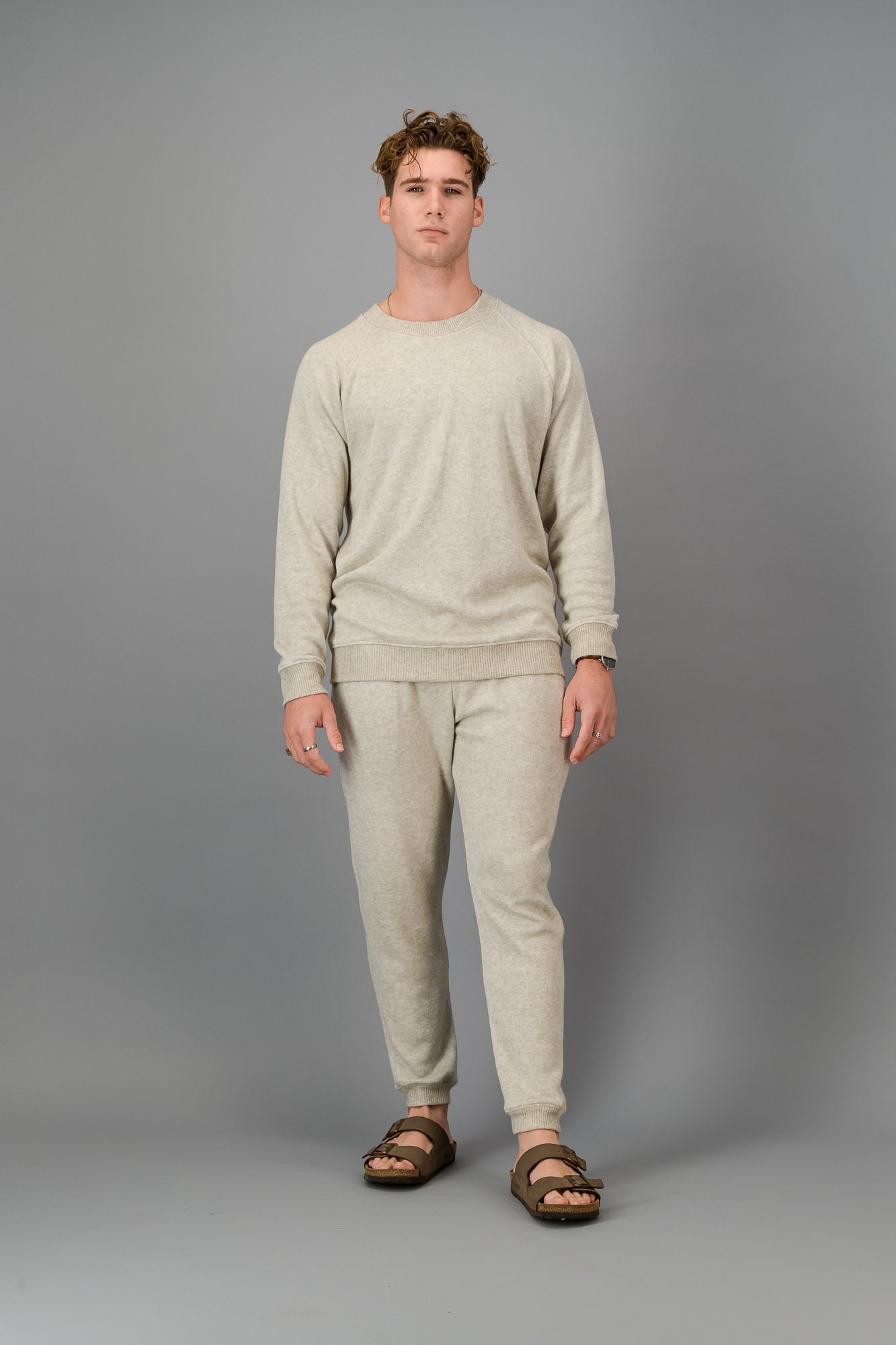 A man in Oatmeal Cashmere-Feel Crew Neck Sweater and matching joggers.