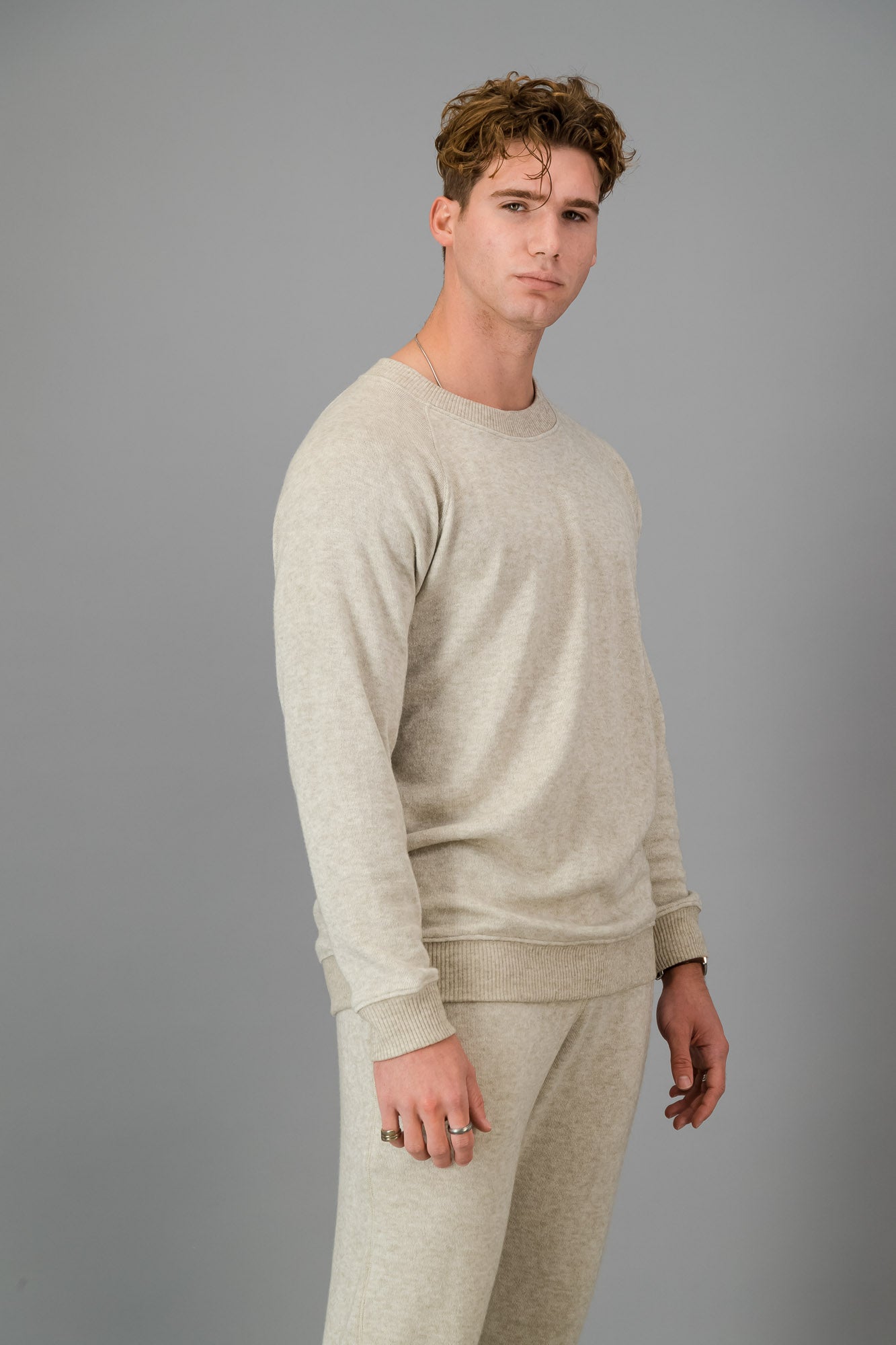 A man in Oatmeal Cashmere-Feel Crew Neck Sweater and matching joggers.