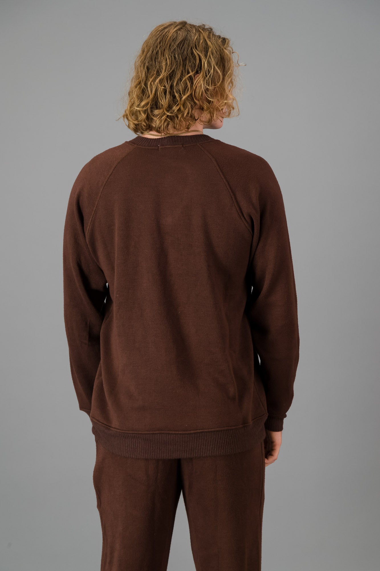 A man in a Chocolate Cashmere-Feel Crew Neck Sweater and matching joggers.