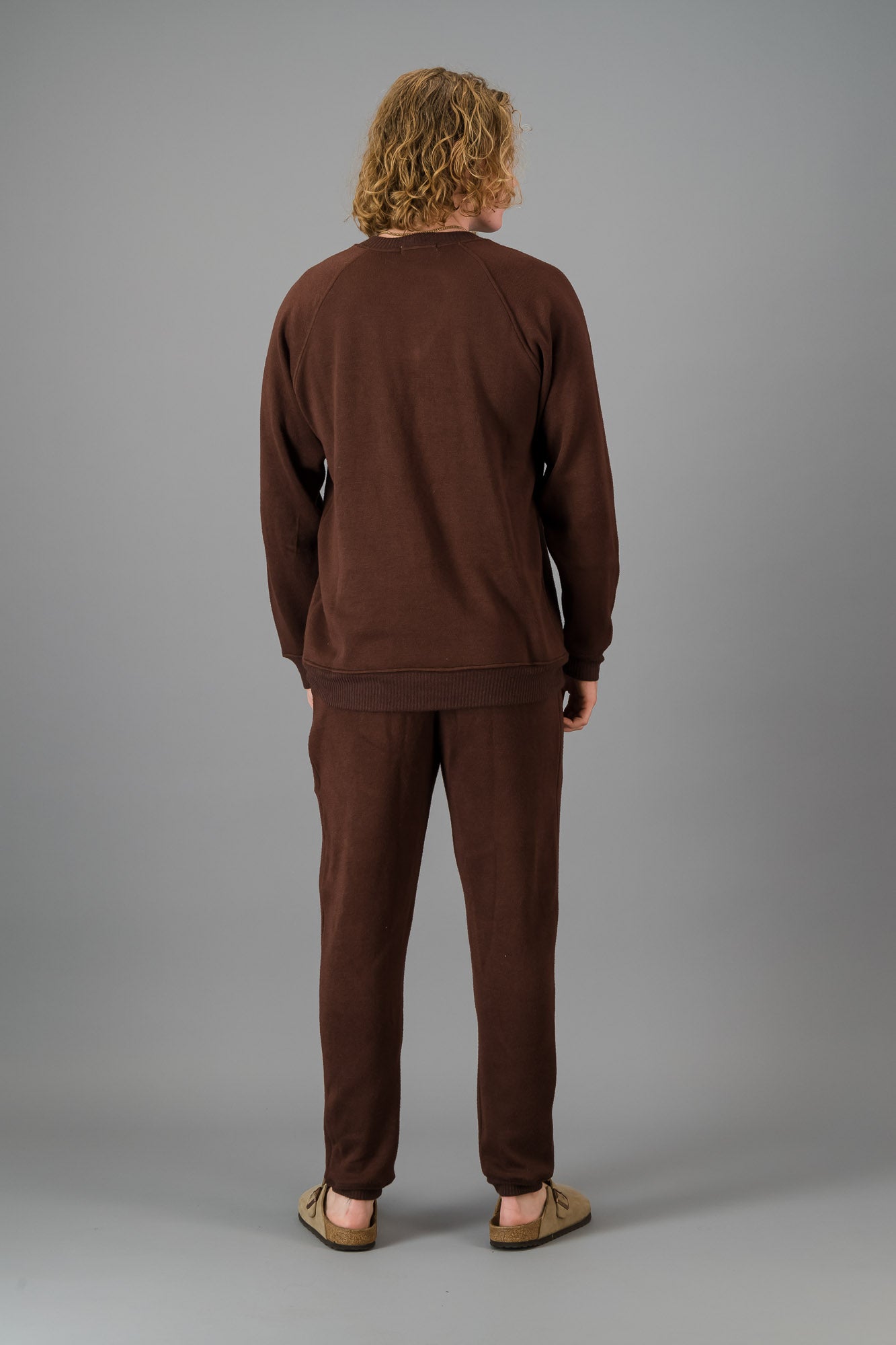 A man in a Chocolate Cashmere-Feel Crew Neck Sweater and matching joggers.