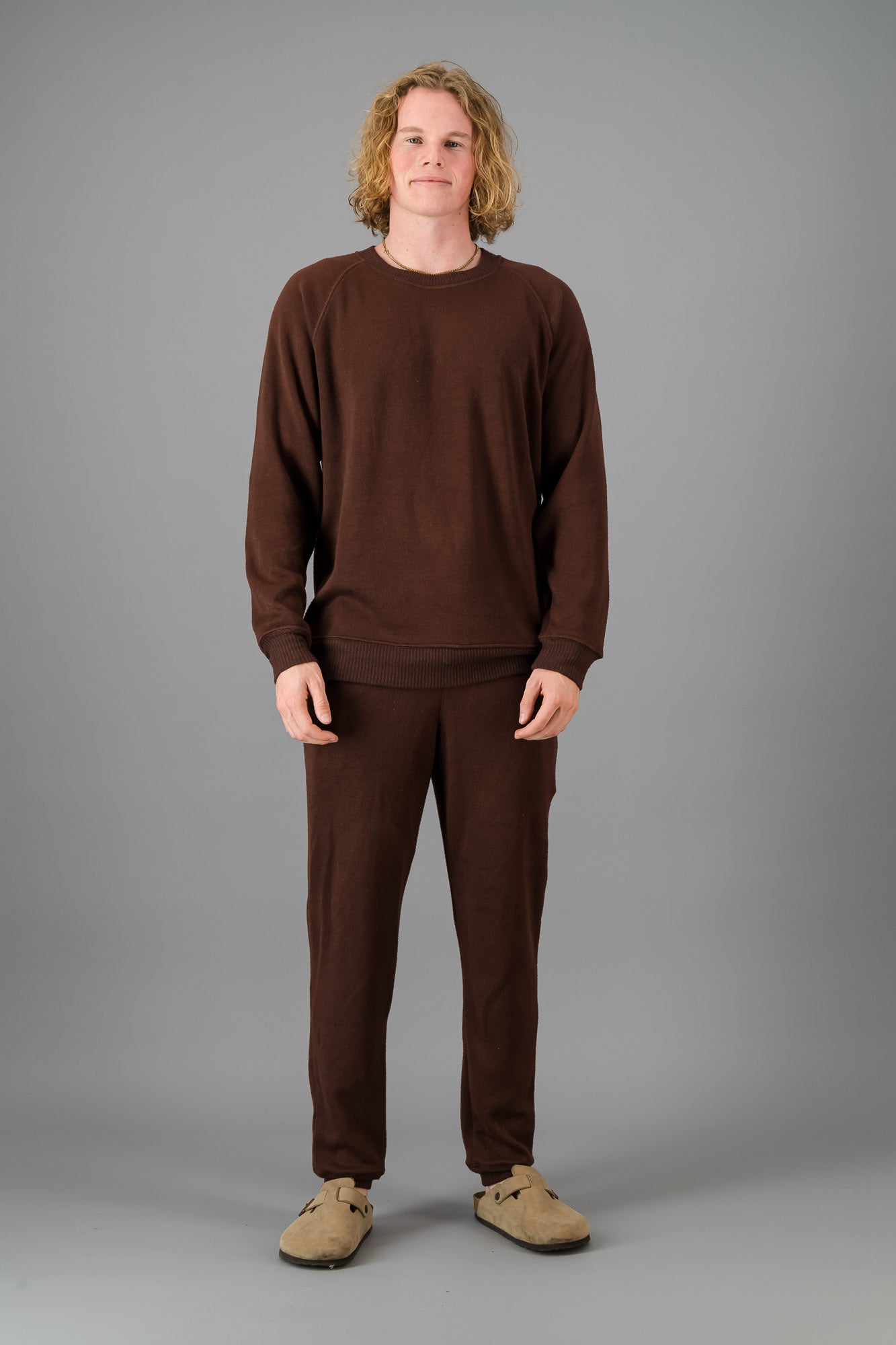 A man in a Chocolate Cashmere-Feel Crew Neck Sweater and matching joggers.