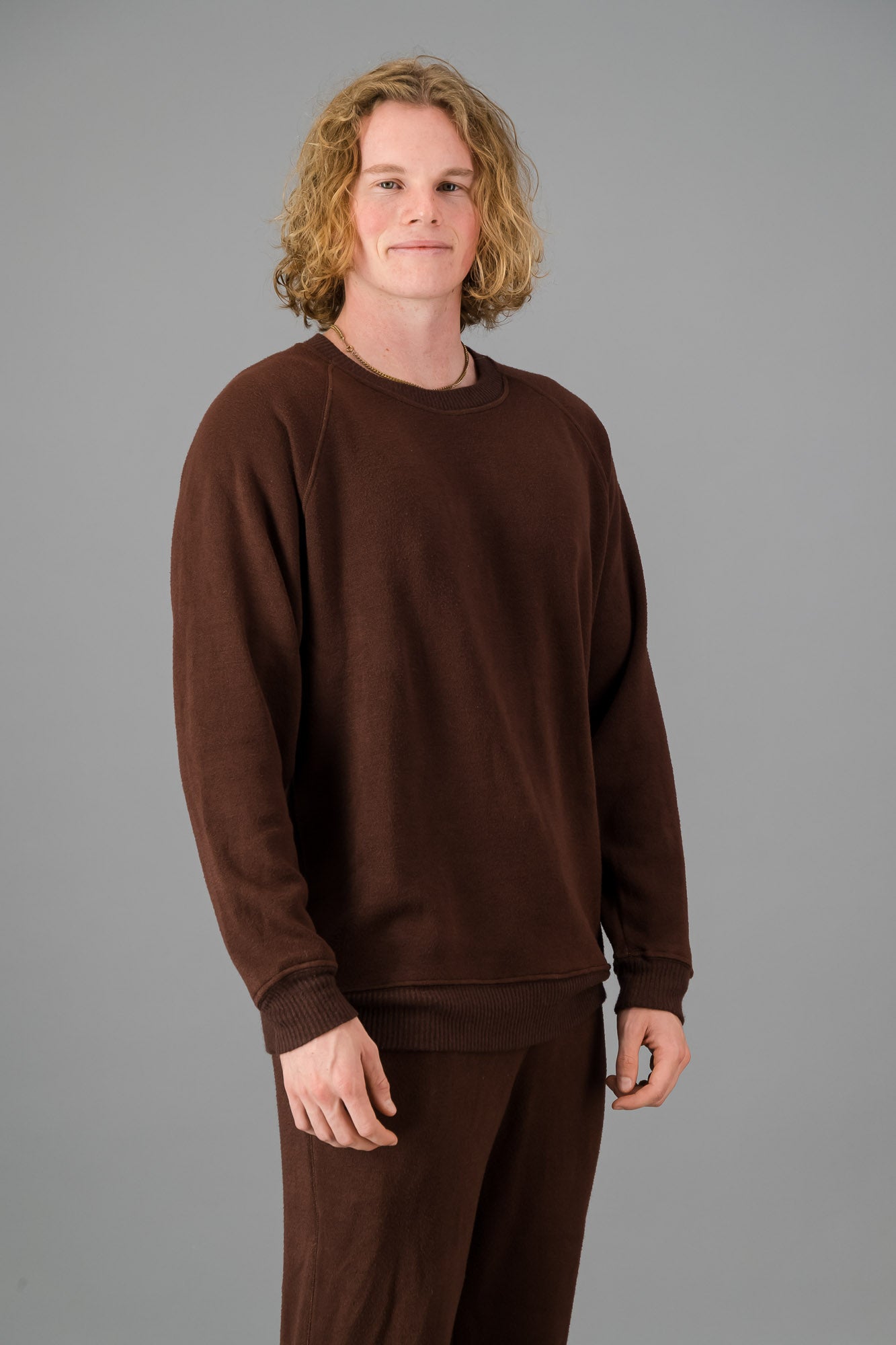 A man in a Chocolate Cashmere-Feel Crew Neck Sweater and matching joggers.