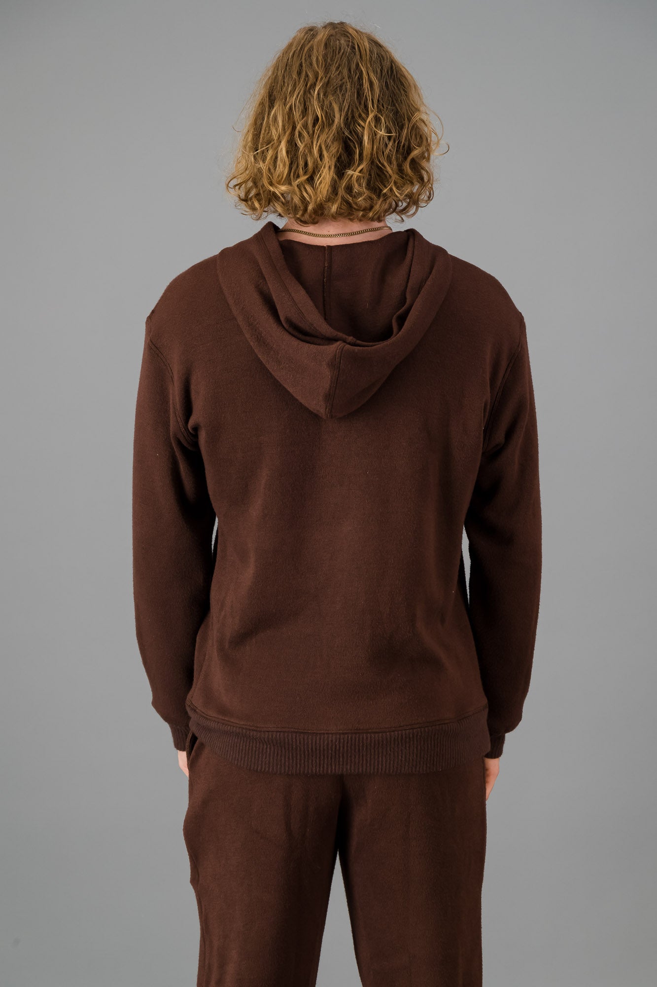 Model with curly, shoulder-length hair wearing a relaxed fit Cashmere-Feel Hoodie in Chocolate.