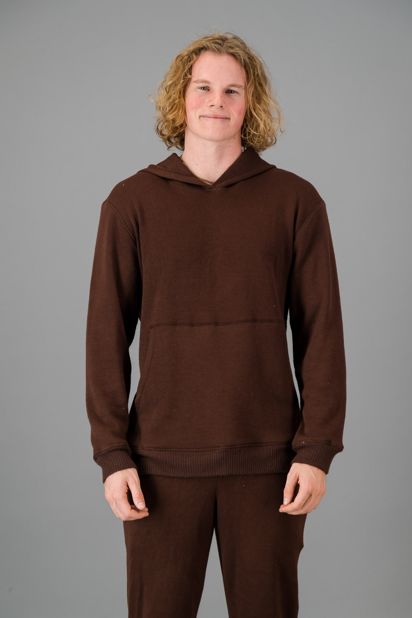 Model with curly, shoulder-length hair wearing a relaxed fit Cashmere-Feel Hoodie in Chocolate.