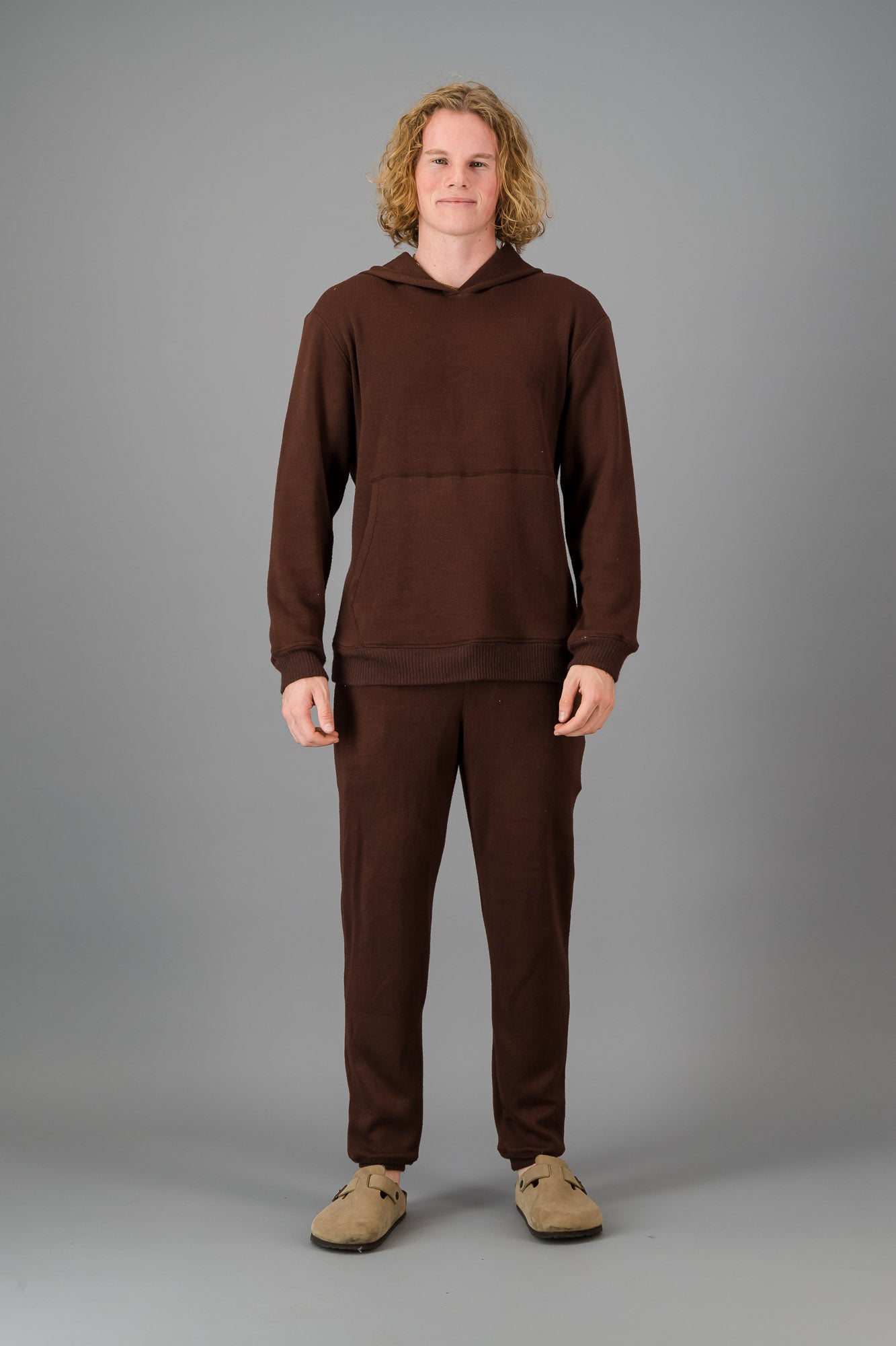 Model with curly, shoulder-length hair wearing a relaxed fit Cashmere-Feel Hoodie in Chocolate.