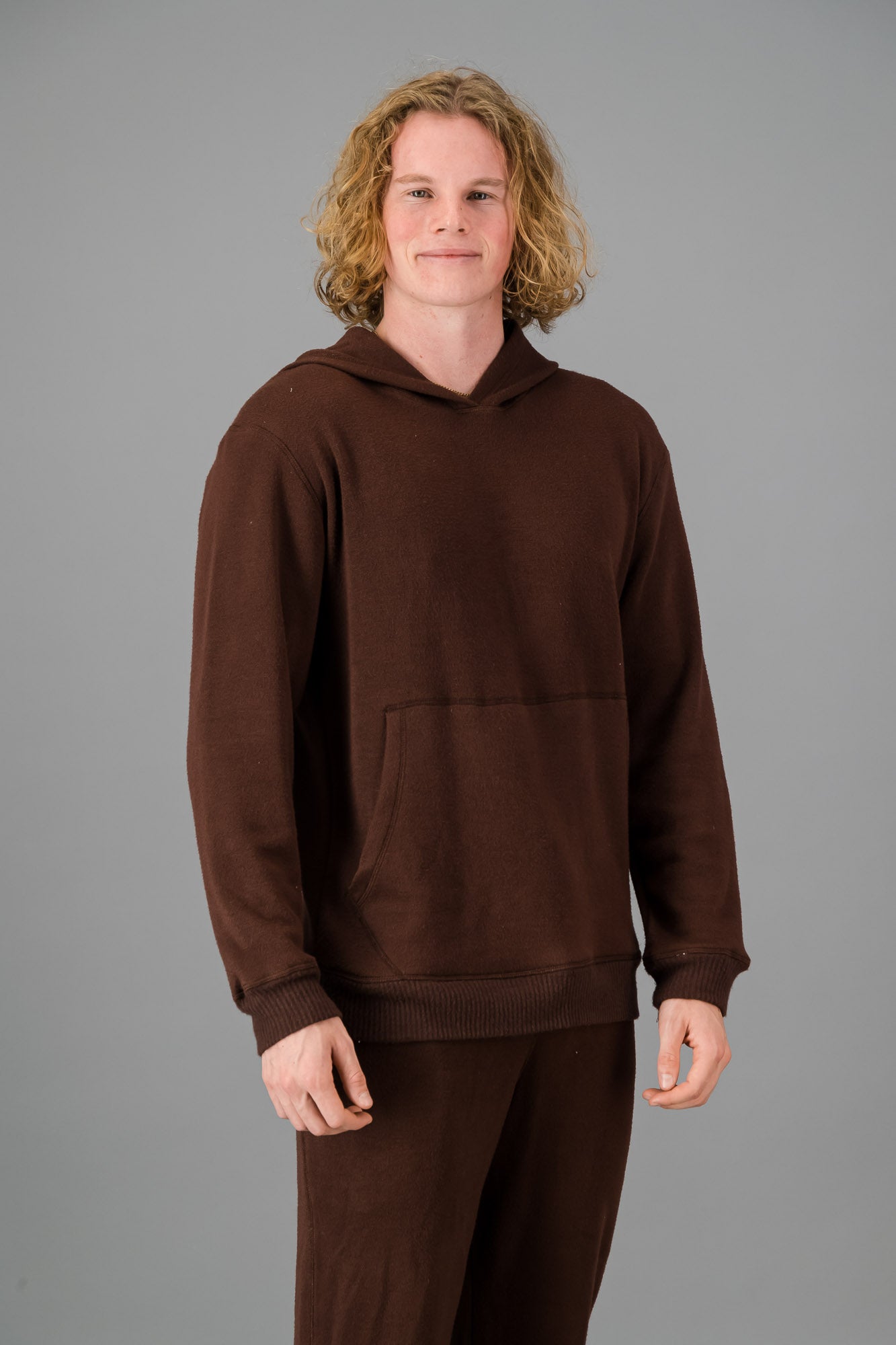 Model with curly, shoulder-length hair wearing a relaxed fit Cashmere-Feel Hoodie in Chocolate.