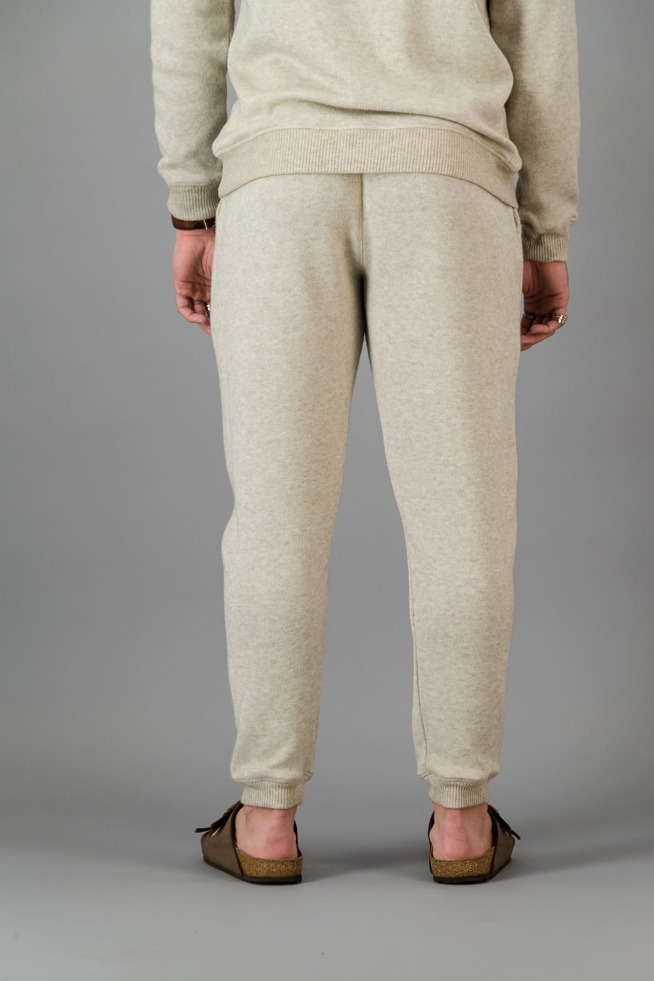 A man wearing Oatmeal Cashmere-Feel Sweatpants with a matching crew neck sweater.