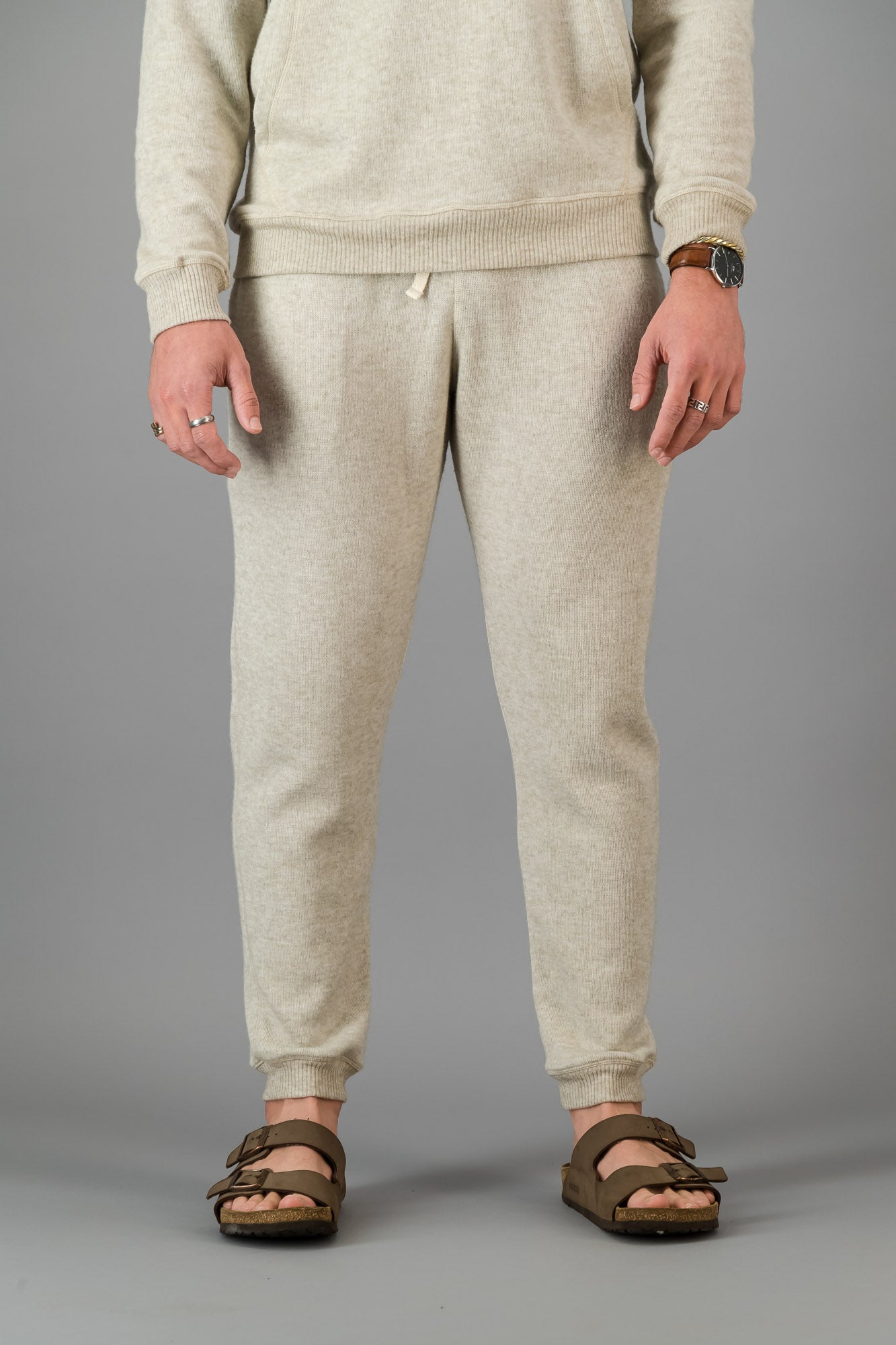 A man wearing Oatmeal Cashmere-Feel Sweatpants with a matching crew neck sweater.