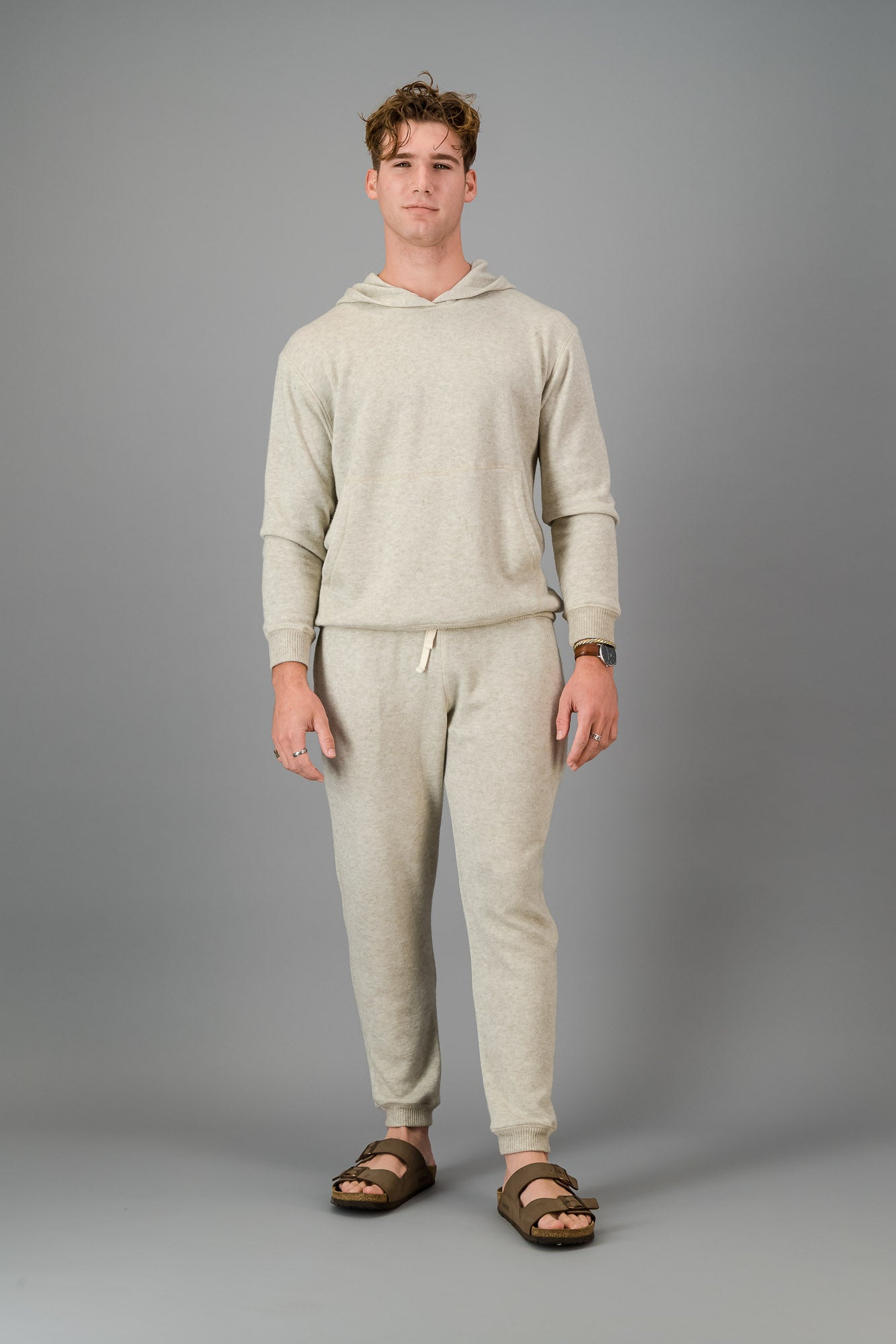 A man wearing Oatmeal Cashmere-Feel Sweatpants with a matching crew neck sweater.