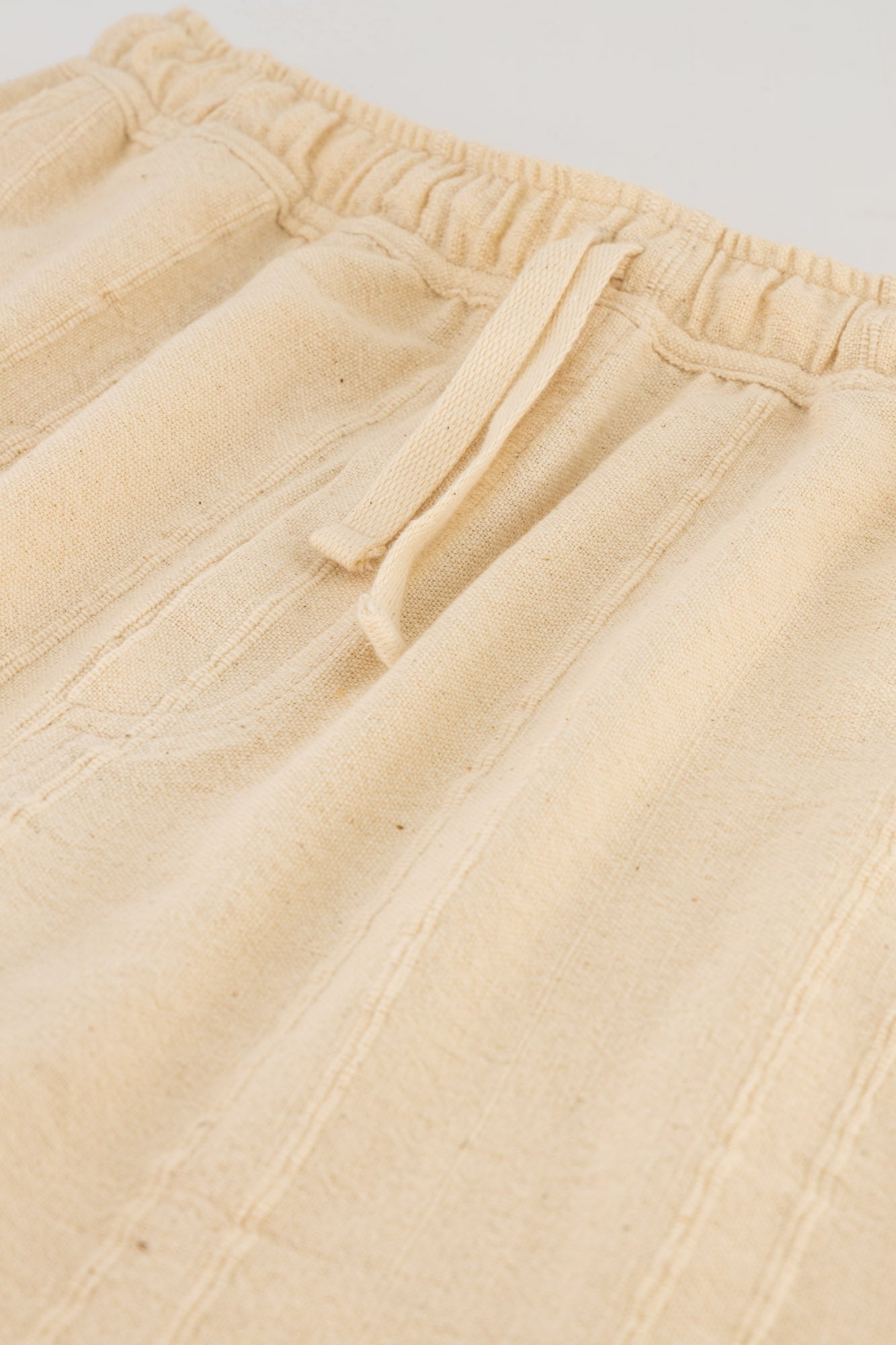 Flat-lay detail shot of cream cotton cord shorts.