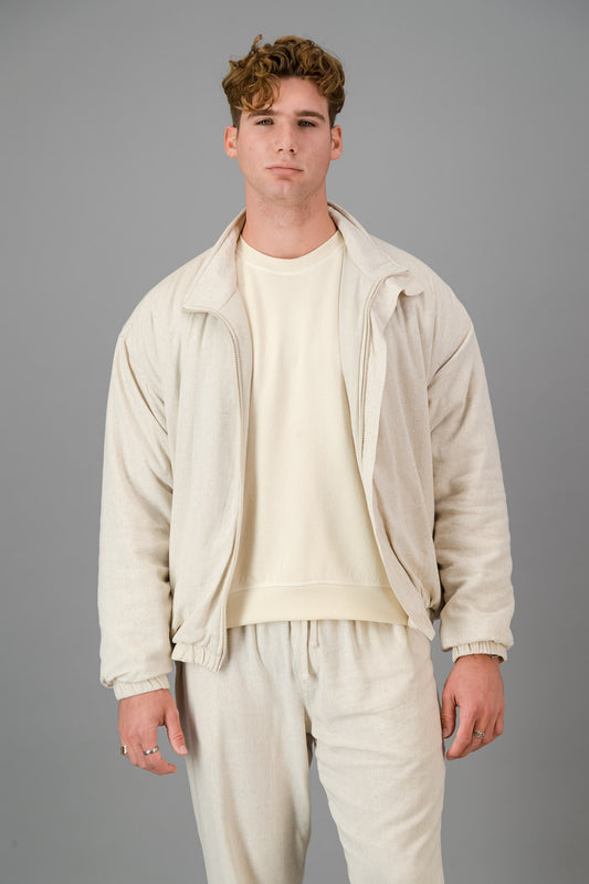 A man stands against a gray background, wearing a stylish and cozy Oatmeal Linen Viscose Bomber and matching pants, looking directly at the camera.