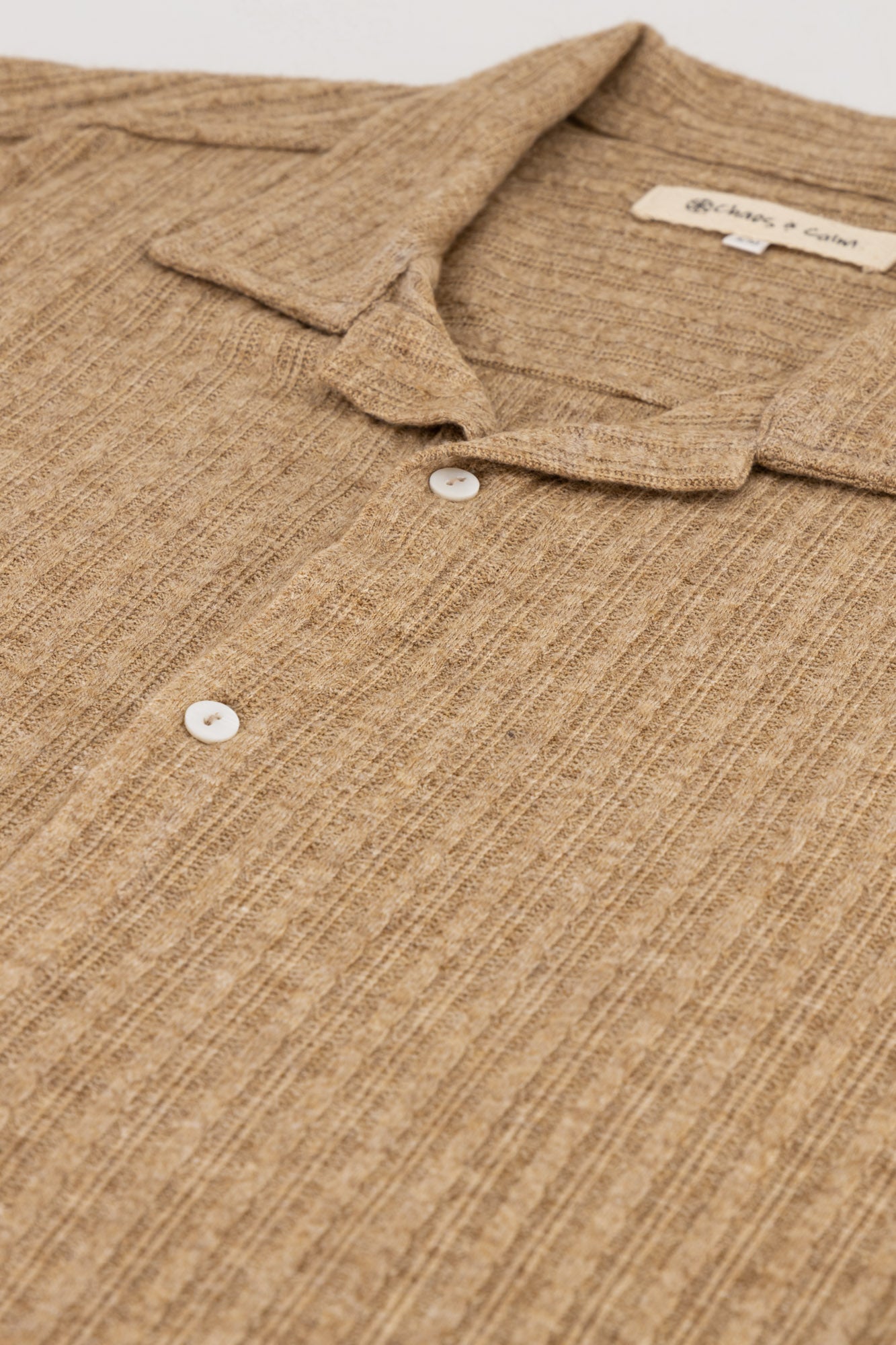 Flat-lay detail shot of a short-sleeve Rayon-rich Cable Knit Shirt in brown.